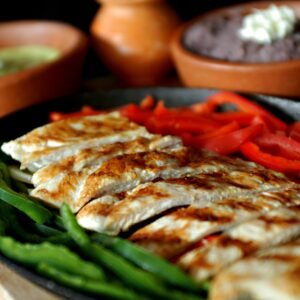 Delicious grilled chicken fajitas with bell peppers, served with traditional Mexican sauces.